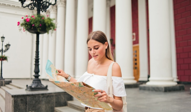 Jonge schoonheid vrouw toerist verkennen stadsplattegrond in stedelijke omgeving tegen kolommen