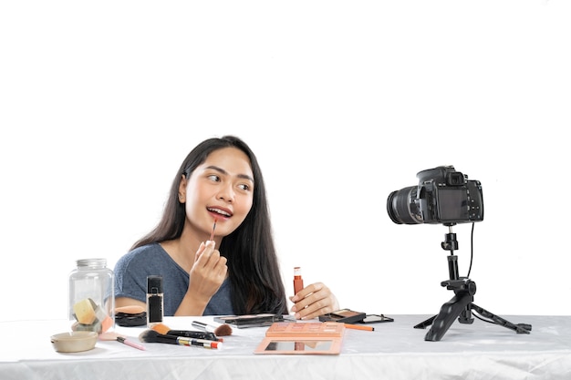 Jonge schoonheid vrouwelijke videoblogger die lippenstift cosmetisch product gebruikt voor camera