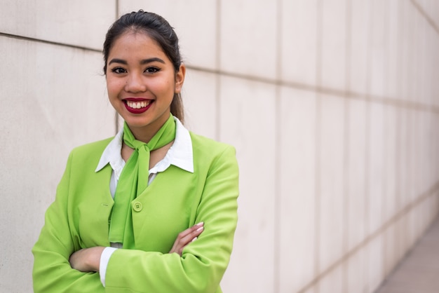 Jonge scortvrouw of bemanning die gekruiste wapens groen glimlachen