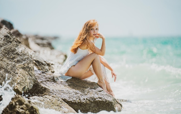 Jonge sensuele vrouw zittend op het strand vrouw ontspannen zittend in de buurt van water op zee geniet van vakantie en we