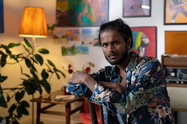 Jonge serene man van Indiase etniciteit die een slim shirt draagt dat in een kunststudio zit