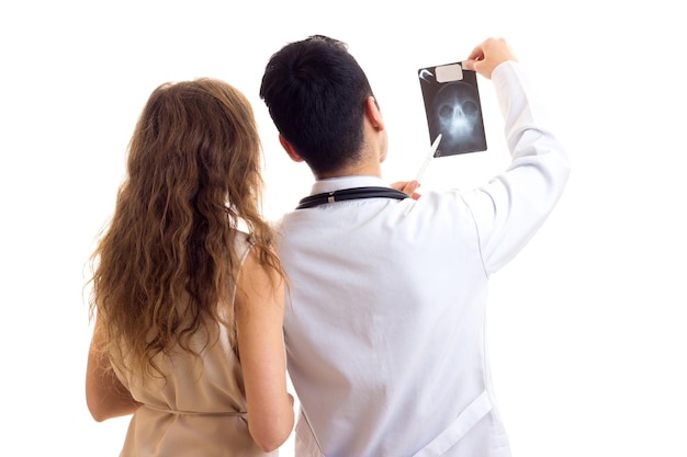 Jonge serieuze arts in witte jurk met stethoscoop die röntgenstraal laat zien aan jonge mooie vrouw