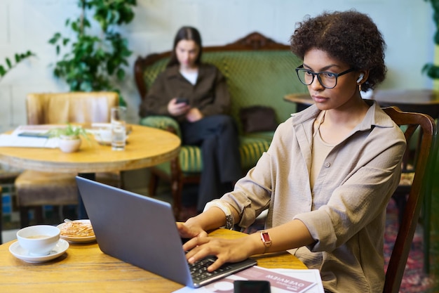 Jonge serieuze vrouwelijke student of analist die naar het scherm van een laptop kijkt