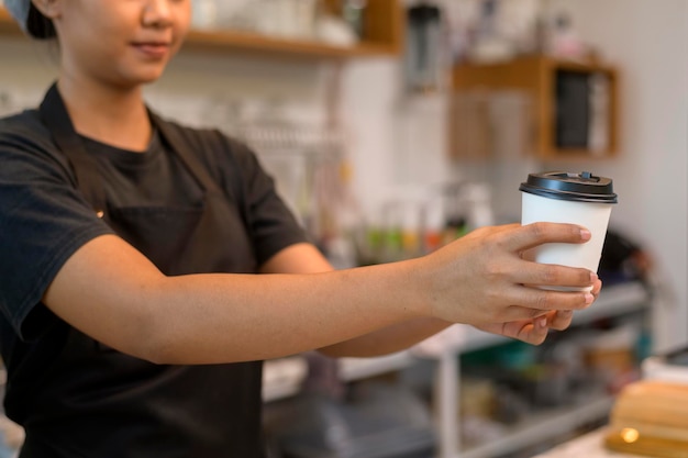 Jonge servicegerichte barista-vrouw die in de coffeeshop werkt