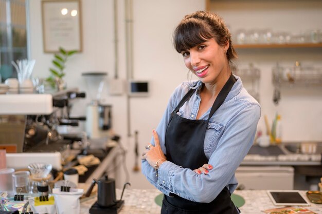 Jonge servicegerichte barista-vrouw die in de coffeeshop werkt