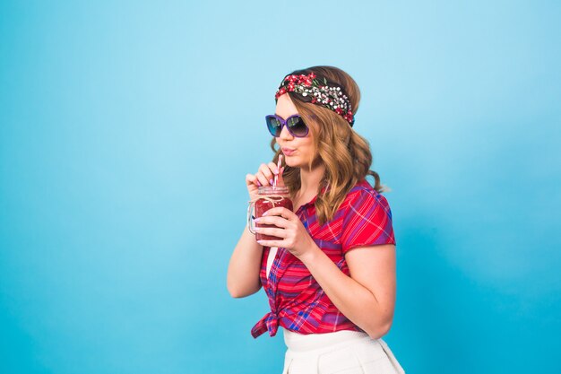 Jonge sexy hipster vrouw drinken lekkere smoothie, vintage outfit, make-up zonnebril, studio lifestyle portret, dessert.