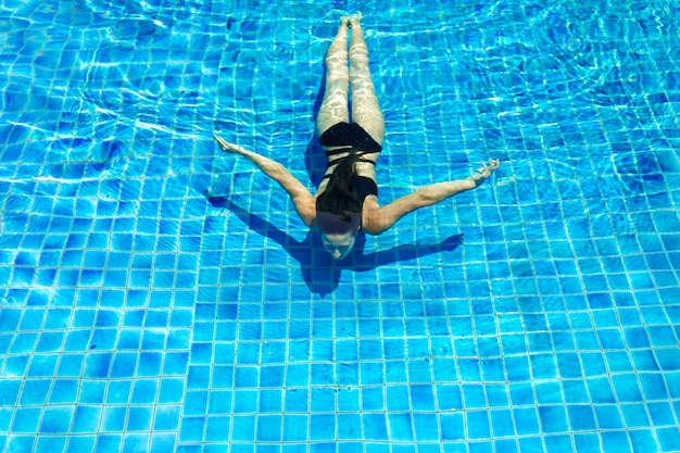 Jonge sexy slanke vrouw ontspannen in het zwembad met kristalhelder water