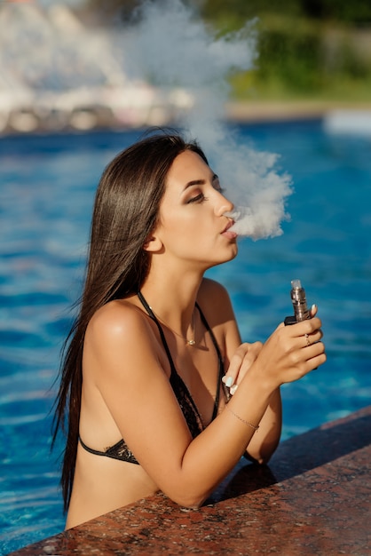 Jonge sexy vrouw is vaping. Een wolk van damp. Hete en sexy vrouw vapen (roken van een e - sigaret) Close-up bekijken. Vapen concept