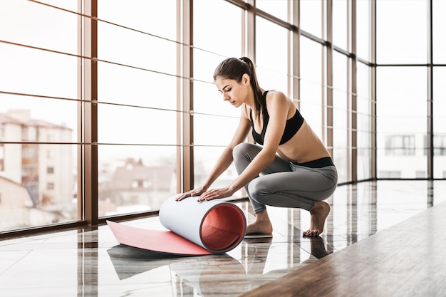 Jonge slanke aantrekkelijke vrouw met lang haar beoefenen van yoga binnenshuis.