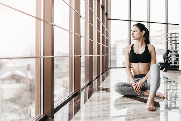 Jonge slanke aantrekkelijke vrouw met lang haar beoefenen van yoga binnenshuis.