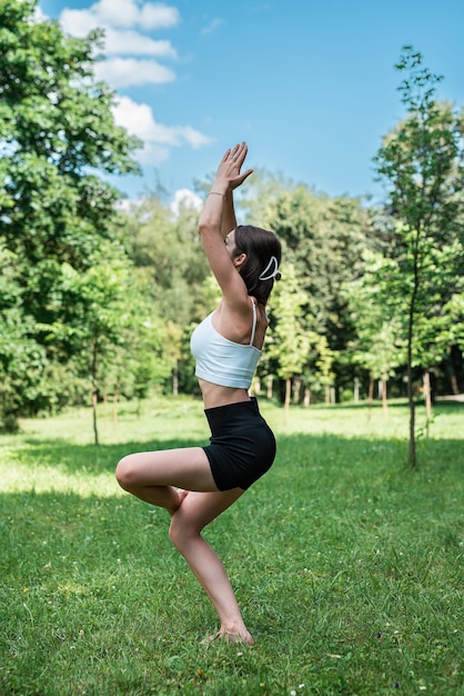 Foto jonge slanke blanke vrouw in sportkleding doet yoga in het park sport in de open lucht