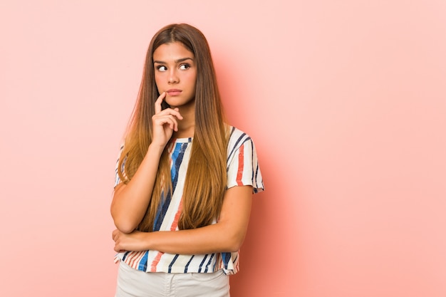 Jonge slanke vrouw die zijdelings met twijfelachtige en sceptische uitdrukking kijkt.