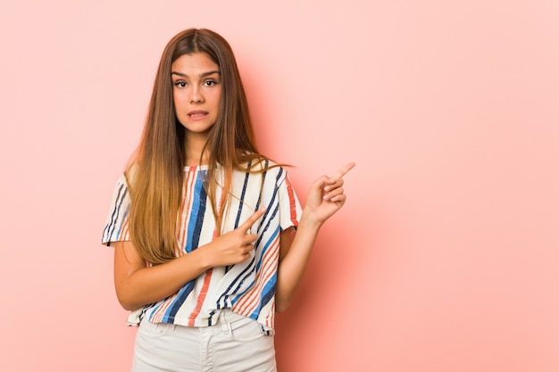 Jonge slanke vrouw geschokt wijzend met wijsvingers naar een kopie ruimte.