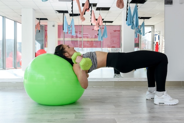 Jonge slanke vrouw in fitness gym rusten op fit pilates bal. Jonge vrouw training op geschiktheidsbal. Gezonde levensstijl