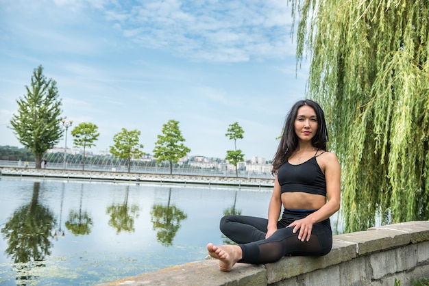 Jonge slanke vrouw in sportkleding zitten en ontspannen rust na ochtend sporttraining. Gezonde levensstijl.