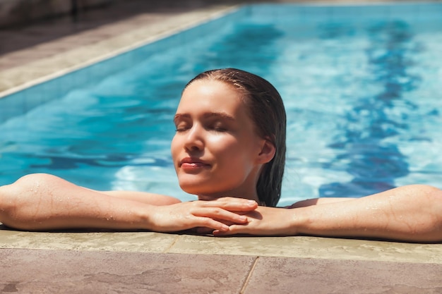 Jonge slanke vrouw in zwembroek ontspannen bij het zwembad