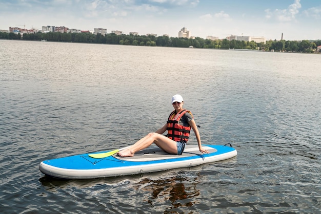 Jonge slanke vrouw rijdt op een SUP-bord op het stadsmeer