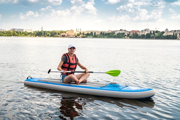 Jonge slanke vrouw rijdt op een SUP-bord op het stadsmeer