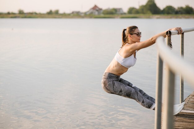 Foto jonge slim fit vrouw doet sport oefening buitenshuis in het park op de zonnige dag