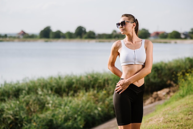 Jonge slim fit vrouw doet sport oefening buitenshuis in het park op de zonnige dag