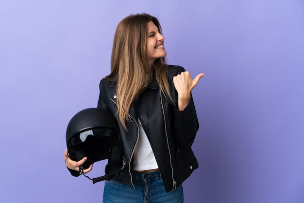 Jonge Slowaakse vrouw met een motorhelm geïsoleerd op paars wijzend naar de zijkant om een product te presenteren