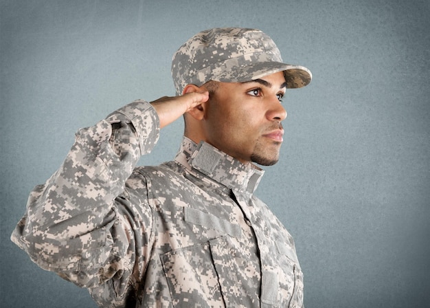 Jonge soldaat salueert tegen een grijze achtergrond