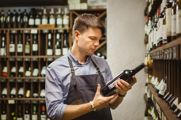 Jonge sommelier met fles rode wijn in kelder