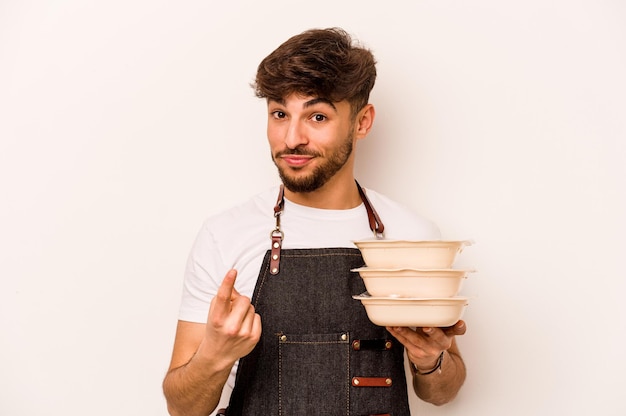 Jonge Spaanse klerk man met een tupperware geïsoleerd op een witte achtergrond wijzend met de vinger naar je alsof uitnodigend dichterbij komen