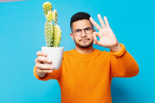 Jonge Spaanse man gelukkige uitdrukking en met een cactus