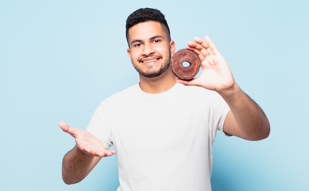 Jonge Spaanse man gelukkige uitdrukking en met een donut