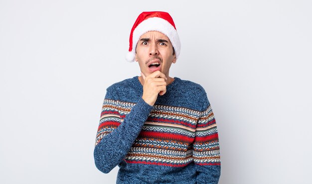 Jonge Spaanse man met mond en ogen wijd open en hand op kin. nieuwjaar en kerstconcept