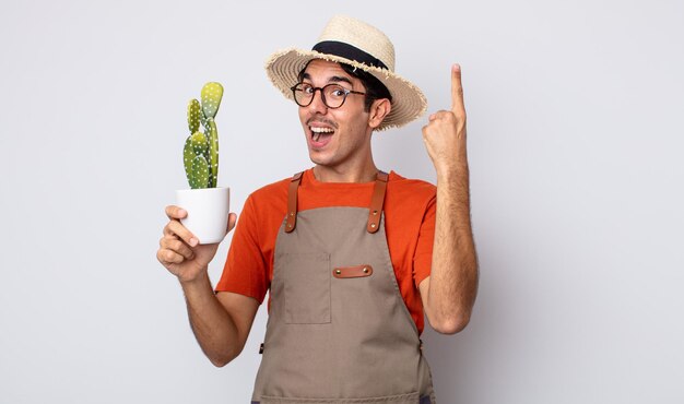 Jonge spaanse man voelt zich een gelukkig en opgewonden genie nadat hij een idee heeft gerealiseerd. tuinman met cactusconcept