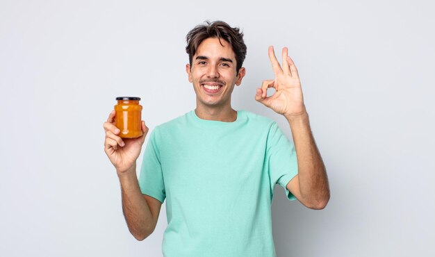 Jonge spaanse man voelt zich gelukkig en toont goedkeuring met een goed gebaar. perzik gelei concept