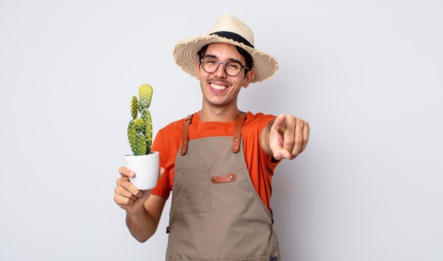 Jonge Spaanse man wijzend op de camera die jou kiest. tuinman met cactusconcept