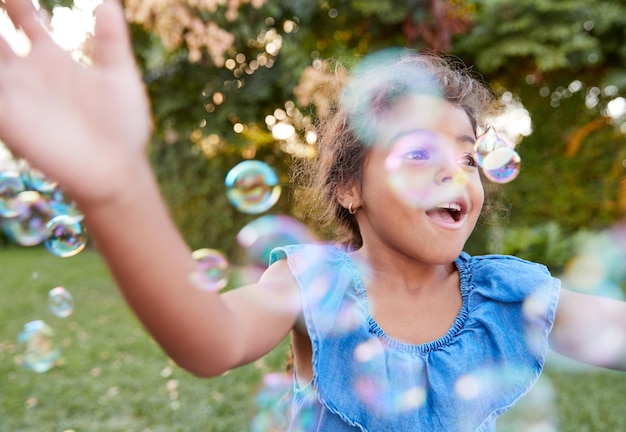 Jonge Spaanse meid jaagt en vangt bubbels in de tuin