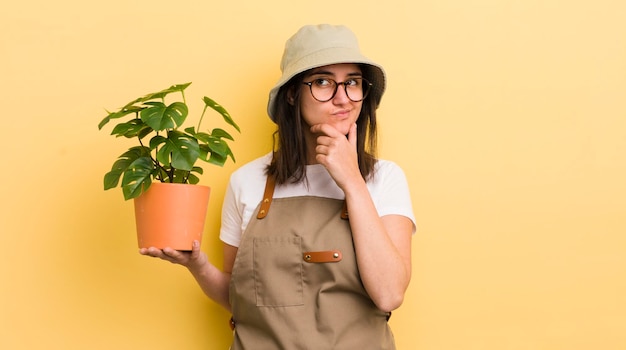 Jonge Spaanse vrouw denkt twijfelachtig en verward tuinman en plantconcept te voelen