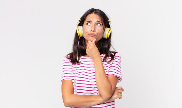 Jonge Spaanse vrouw denkt, voelt zich twijfelachtig en verward muziek luisteren met een koptelefoon