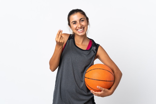 Jonge Spaanse vrouw die basketbal over geïsoleerd wit speelt die geldgebaar maakt