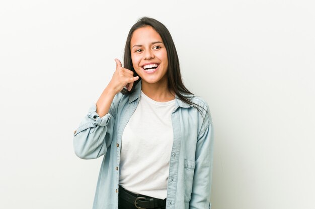 Jonge Spaanse vrouw die een mobiel telefoongesprekgebaar met vingers toont.