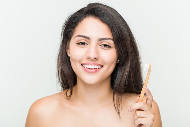 Jonge Spaanse vrouw die een tandenborstel gelukkig, glimlachend en vrolijk houdt
