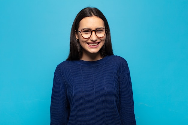 jonge Spaanse vrouw die er blij en maf uitziet met een brede, grappige, gekke glimlach en ogen wijd open