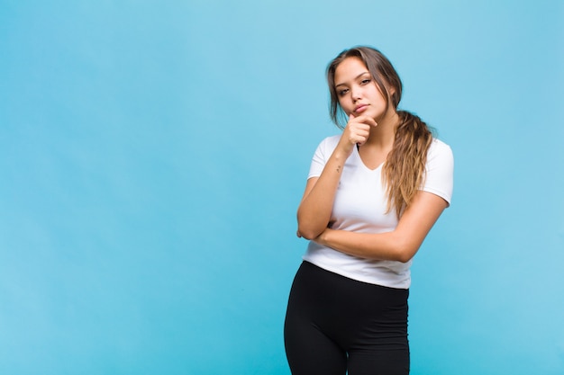 Jonge Spaanse vrouw die ernstig, verward, onzeker en attent kijkt, twijfelt tussen opties of keuzen