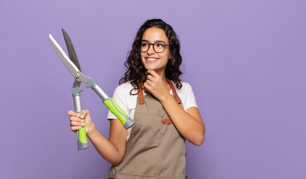 Jonge Spaanse vrouw die gelukkig glimlacht en dagdroomt of twijfelt, die naar de kant kijkt