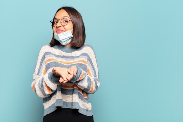 Jonge Spaanse vrouw die gelukkig glimlacht met vriendelijke, zelfverzekerde, positieve blik, die een voorwerp of concept aanbiedt en toont