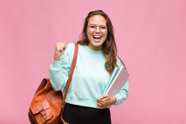 Jonge Spaanse vrouw die geschokt, opgewonden en gelukkig voelt, lacht en succes viert, wauw zegt!