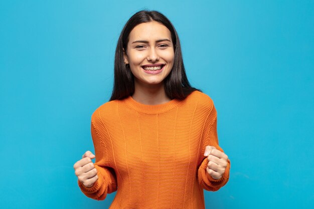 Jonge Spaanse vrouw die geschokt, opgewonden en gelukkig voelt, lacht en succes viert, wauw zegt!