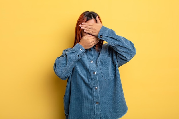 Jonge Spaanse vrouw die gezicht bedekt met beide handen en nee zegt tegen de camera! foto's weigeren of foto's verbieden