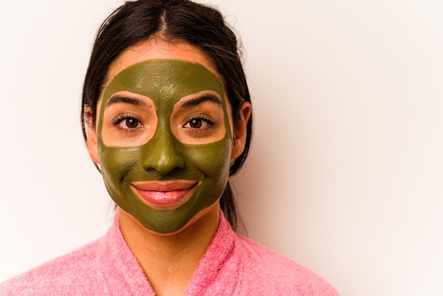 Jonge Spaanse vrouw die gezichtsmasker draagt dat op witte achtergrond wordt geïsoleerd