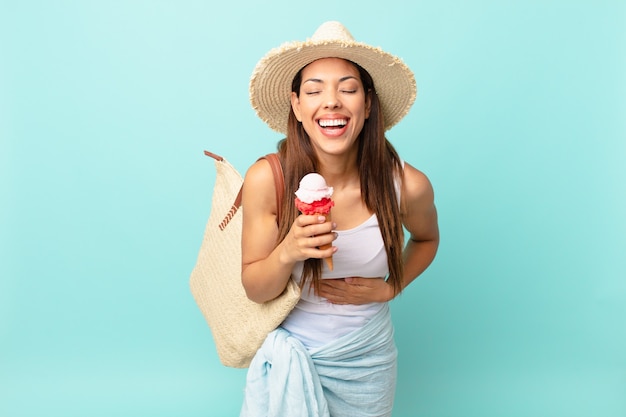 Jonge spaanse vrouw die hardop lacht om een hilarische grap en een ijsje vasthoudt. zomer concept