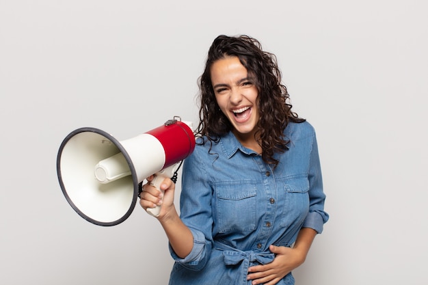 Jonge Spaanse vrouw die hardop lacht om een of andere hilarische grap, zich gelukkig en opgewekt voelt, plezier heeft